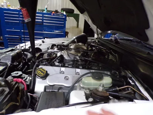 Close-up of an engine bay during service, with the shop's blue tool cabinets behind