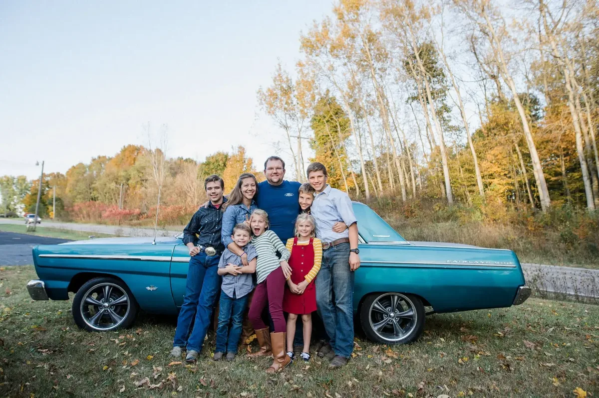 Bryan and Lisa Ford with their children beside a classic turquoise car
